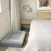 Small grey dog bed placed beside a bedroom setup