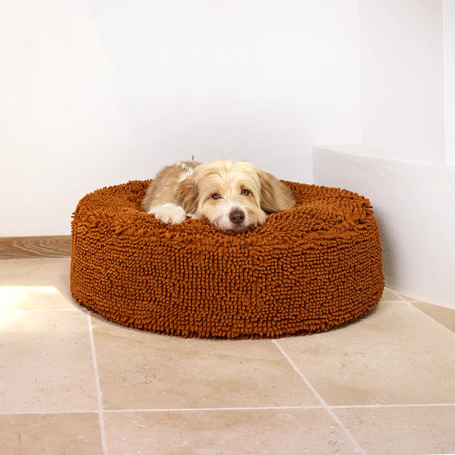 A dog rests on a medium-sized brown pet bed with a textured surface.