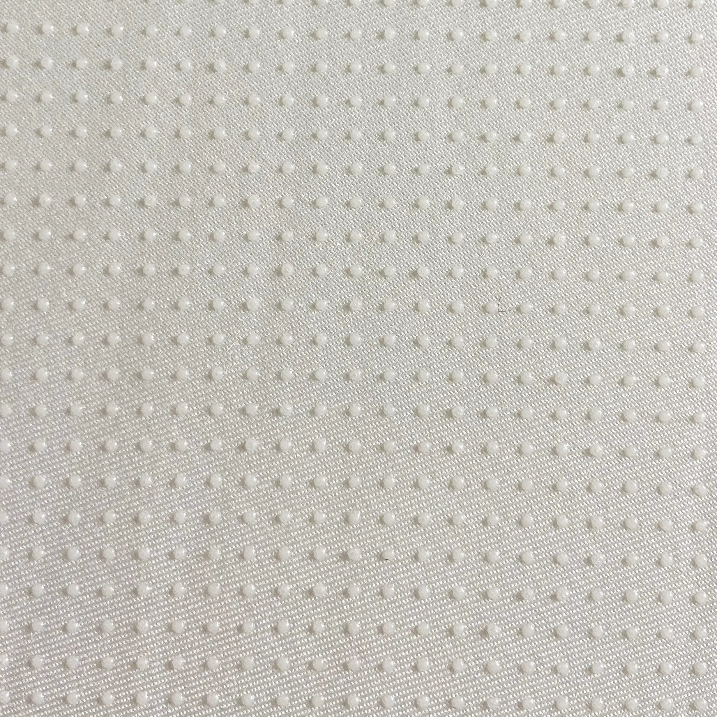 Close-up texture of a white non slip dog bed fabric with small raised dots