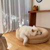 Samoyed dog resting on a large beige dog bed