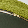 Close-up of a green dog bed with a textured cover and a gold zipper