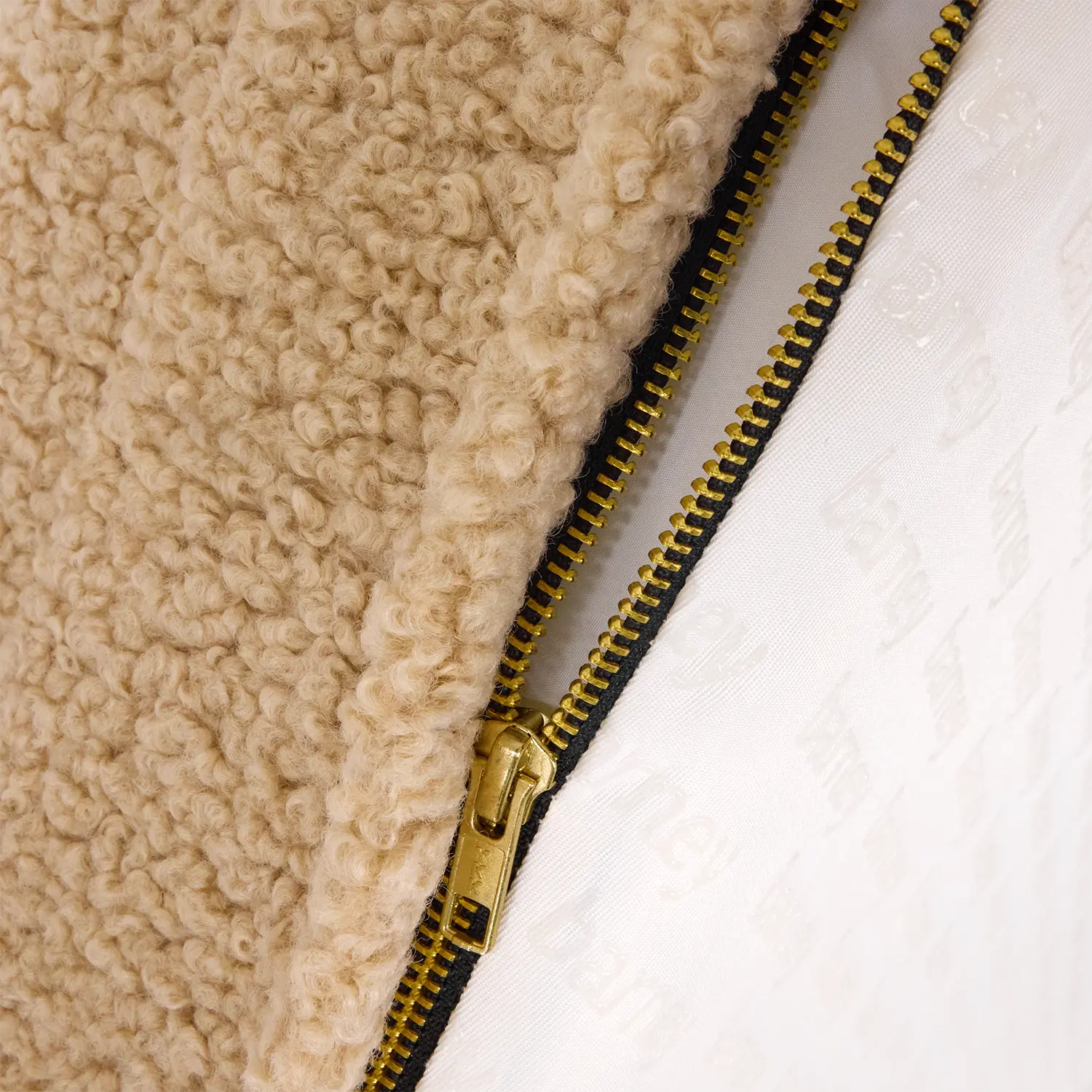 Close-up of a beige dog bed with a gold zipper detail.