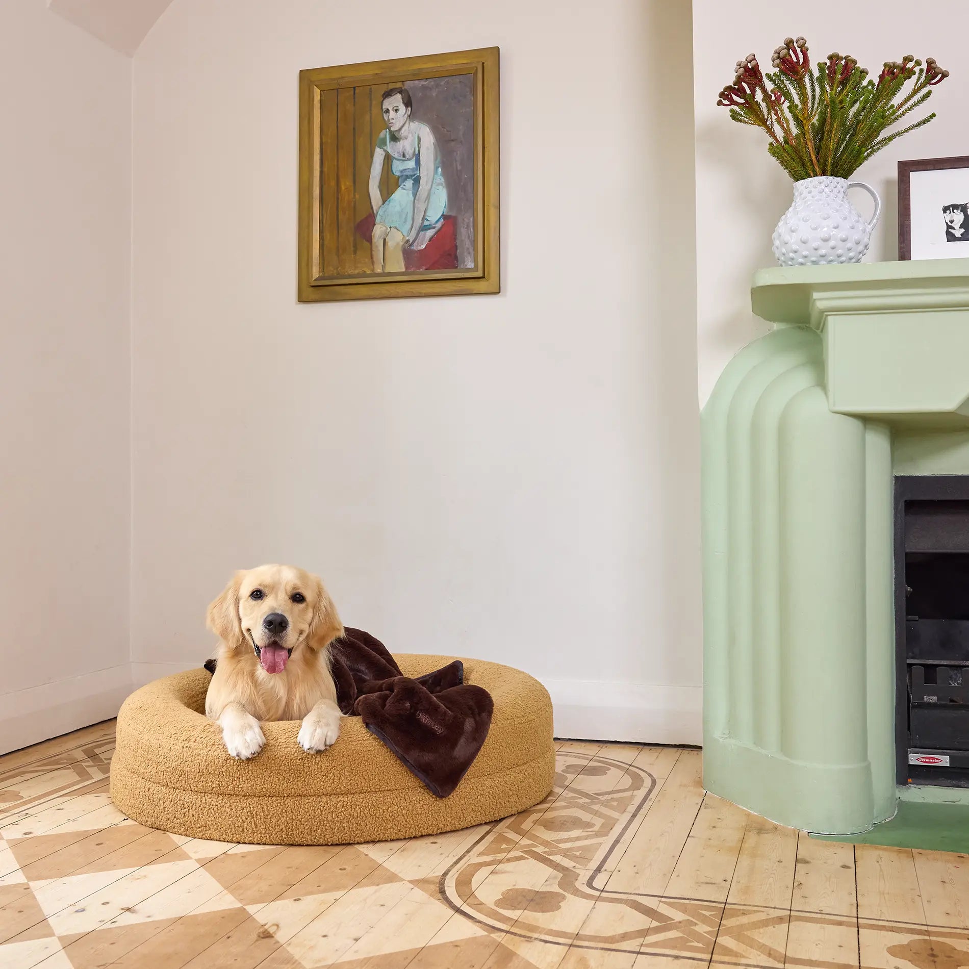 Golden Retriever lying on a medium-sized mud-coloured dog bed with a brown blanket