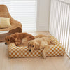 Two golden retrievers resting on a mustard checkered dog bed